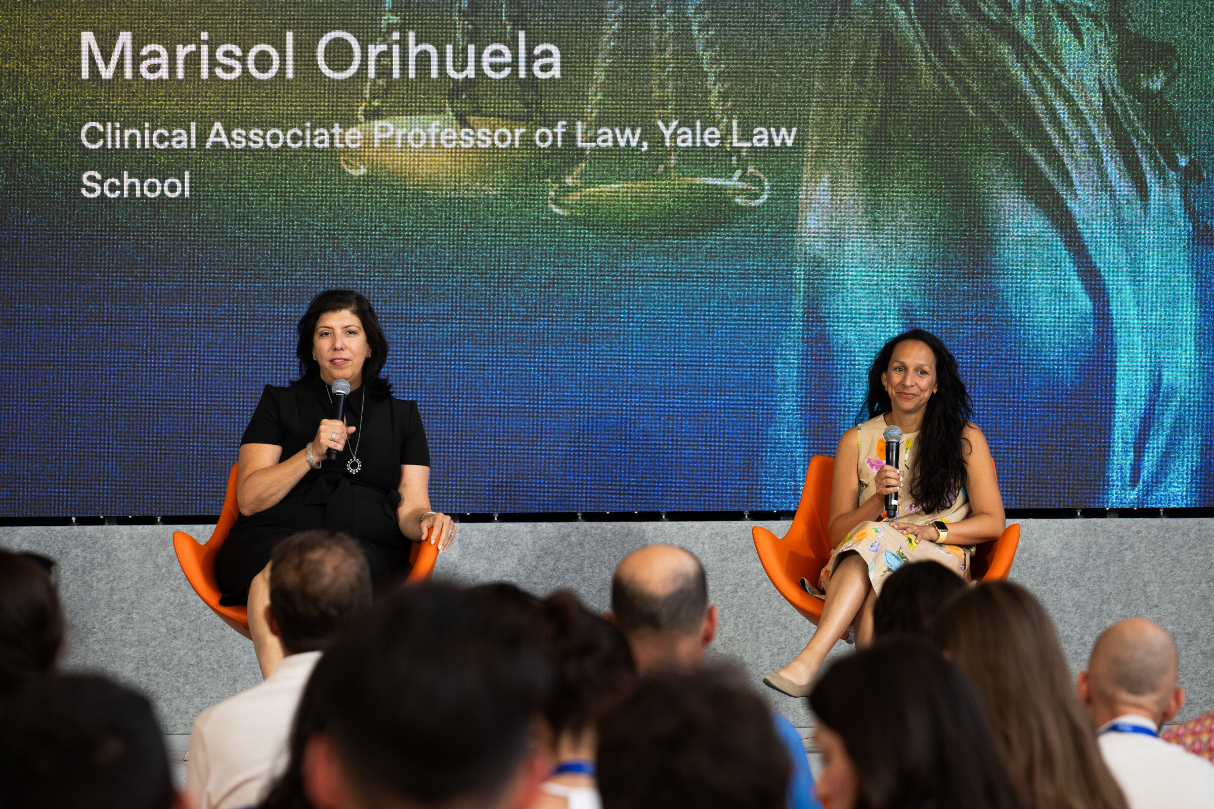 Judge Madeline Singas and Prof. Marisol Orihuela on the panel stage. They are both holding microphones while judge Singas, dressed in black, speaks. 