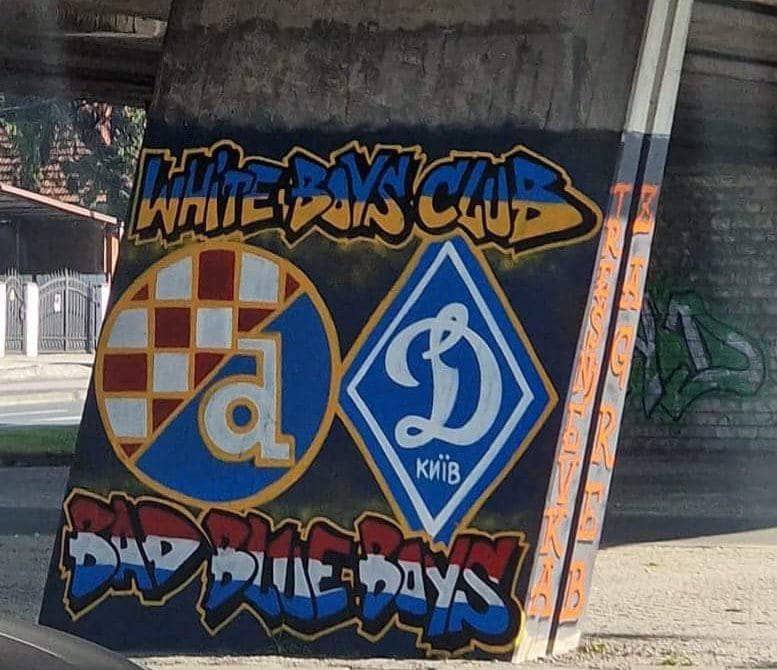 Σε αυτήν την εικόνα φαίνεται μια τοιχογραφία με το σήμα της κροατικής ποδοσφαιρικής ομάδας Ντιναμό Ζάγκρεμπ και δίπλα το σήμα της ουκρανικής ποδοσφαιρικής ομάδας Ντιναμό Κιέβου. Επάνω από τη τοιχογραφία αναγράφεται «White Boys Club» και στο κάτω μέρος «Bad Blue Boys».