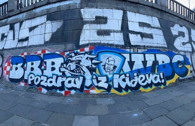 Σε αυτή την εικόνα φαίνεται μια τοιχογραφία με το έμβλημα των φαντικών οπαδών της κροατικής πδοδοσφαιρικής ομάδας Ντιναμό Ζάγκρεμπ (Bad Blue Boys/BBB) και από δίπλα το έμβλημα των φανατικών οπαδών της ουκρανικής ποδοσφαιρικής ομάδας Ντιναμό Κιέβου (White Boys Club/WBC).
