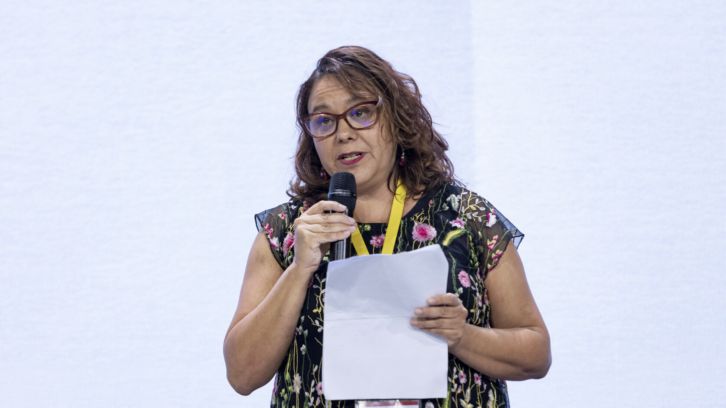 Marcela Turati holding the microphone and a piece of paper while stood on the main stage of the iMEdD International Journalism Forum. She is giving her presentation for the lightning talk series "Reflections on press freedom or lack thereof".
Caption: Photo: Christos Karageorgakis 