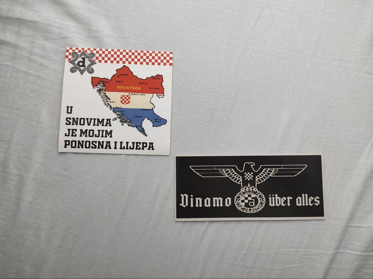 This photo shows two stickers with content related to the fan movement of the Croatian football team Dinamo Zagreb. One shows a map of Croatia in the colours of the Croatian flag. The second has an eagle with open wings, at the base of which is the symbol of Dynamo Zagreb. On the same sticker is the phrase 'Dynamo uber alles'.