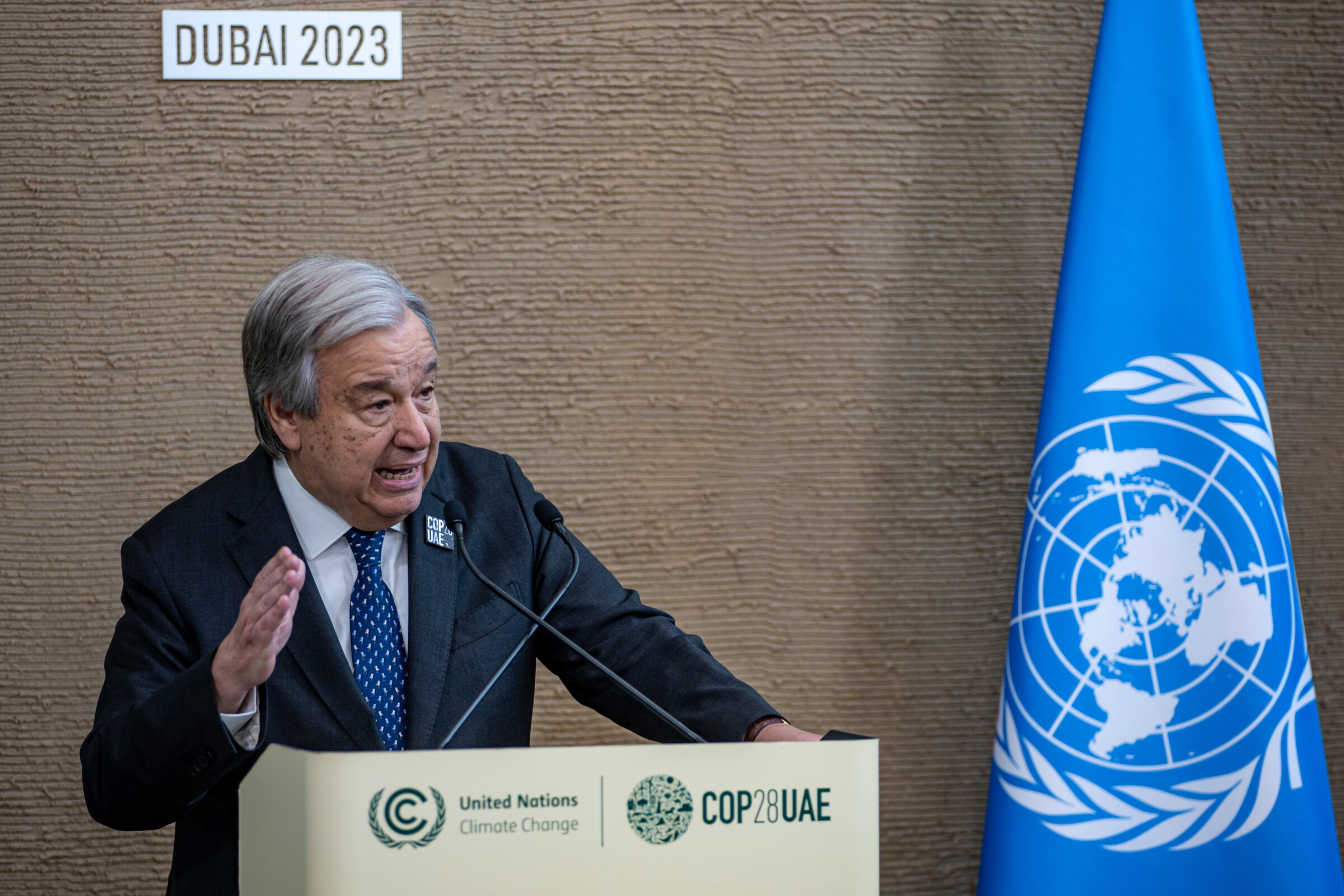 United Nations Secretary-General, Antonio Guterres is stood behind a podium next to a flag with the UN logo. He is addressing journalists during COP 28, in Dubai
Photo: Martin Divisek, EPA, 11/12/2023
