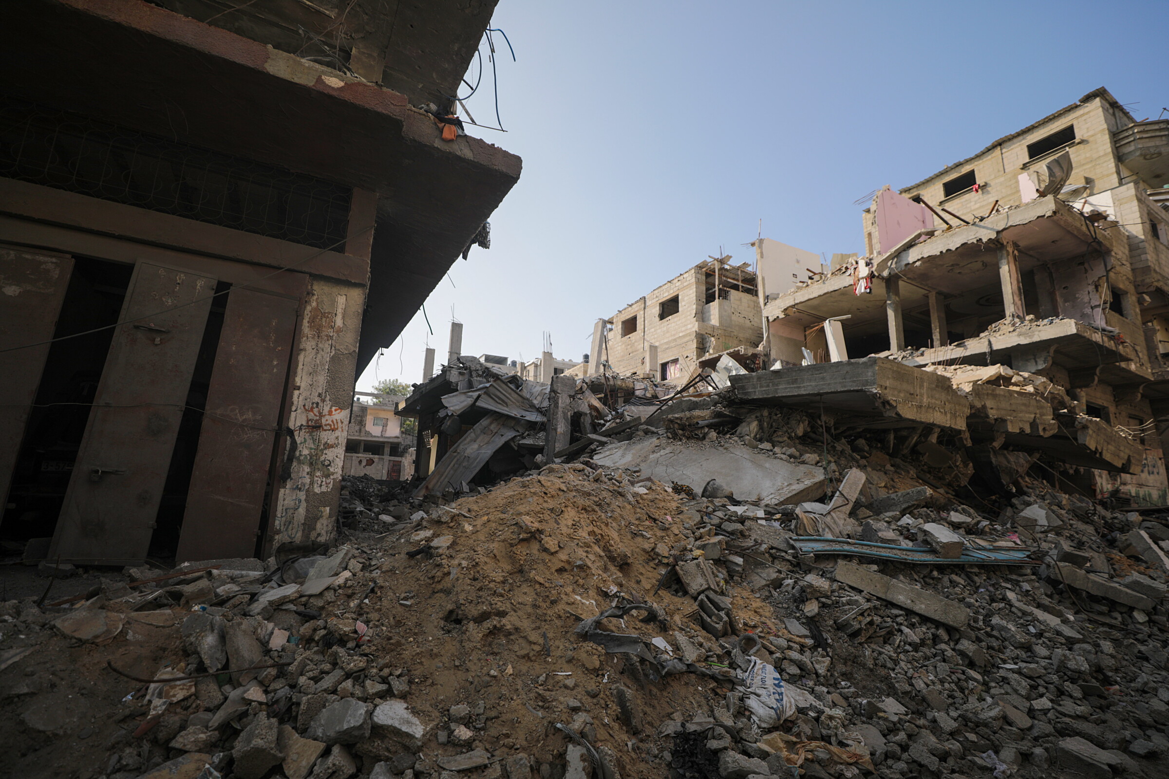 Τρία κατεστραμμένα κτίρια στο βάθος και μπροστά τους συντρίμμια, χώμα και μπάζα. Η καταστροφή οφείλεται στην ισραηλινή αεροπορική επιδρομή στον προσφυγικό καταυλισμό Al Nusairat στη νότια Γάζα. Φωτογραφία: Mohammer Saber, EPA, 31/12/2023