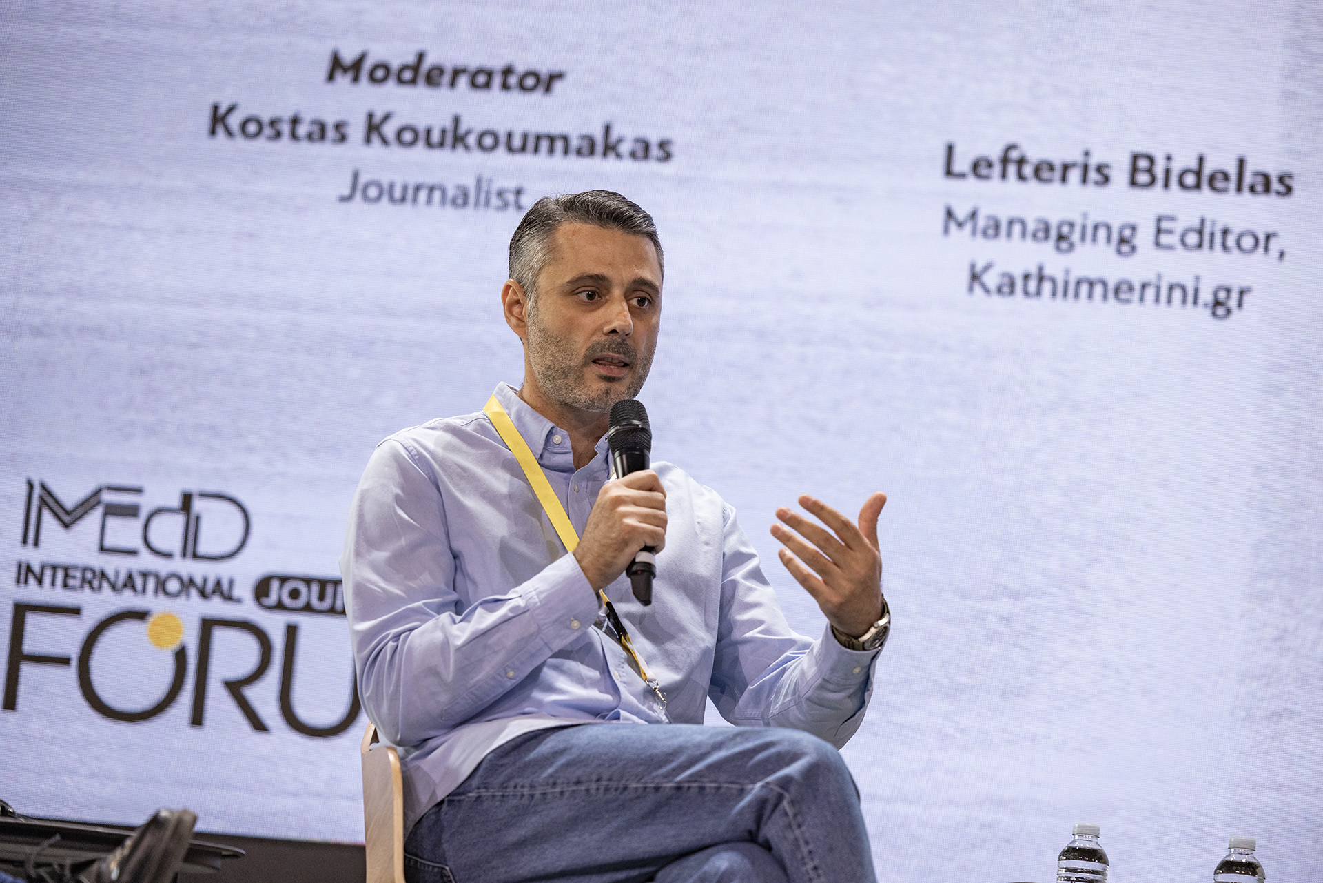 Lefteris Bintelas, Managing Director of Kathimerini.gr, speaks holding a microphone, in the context of the panel "We need to talk about the far right, but how?", held at the iMEdD International Journalism Forum in September 2023.