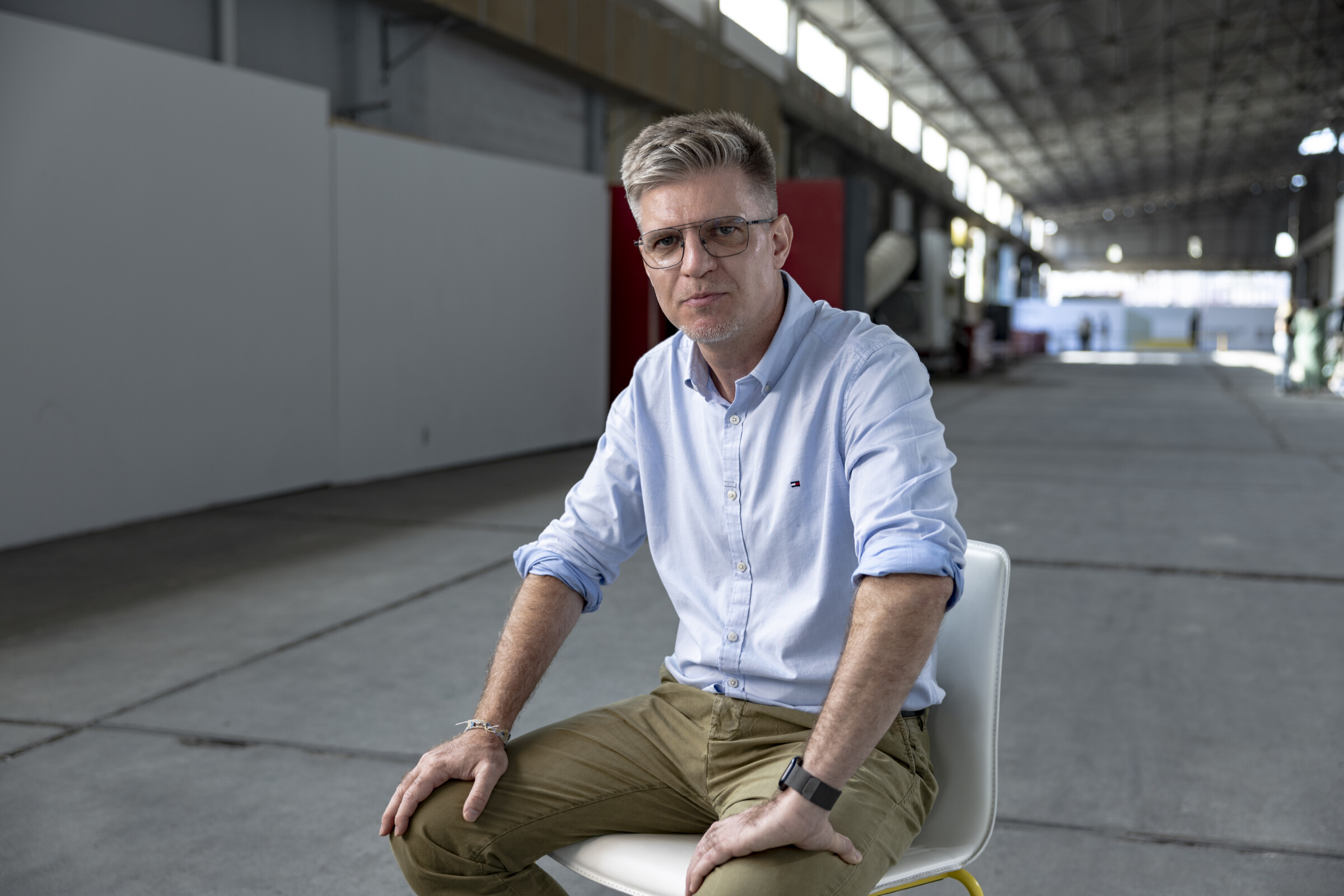 Paul Radu sitting on a chair at the entrance of the venue, where the iMEdD 2024 International Journalism Forum took place, looking straight at the camera. 