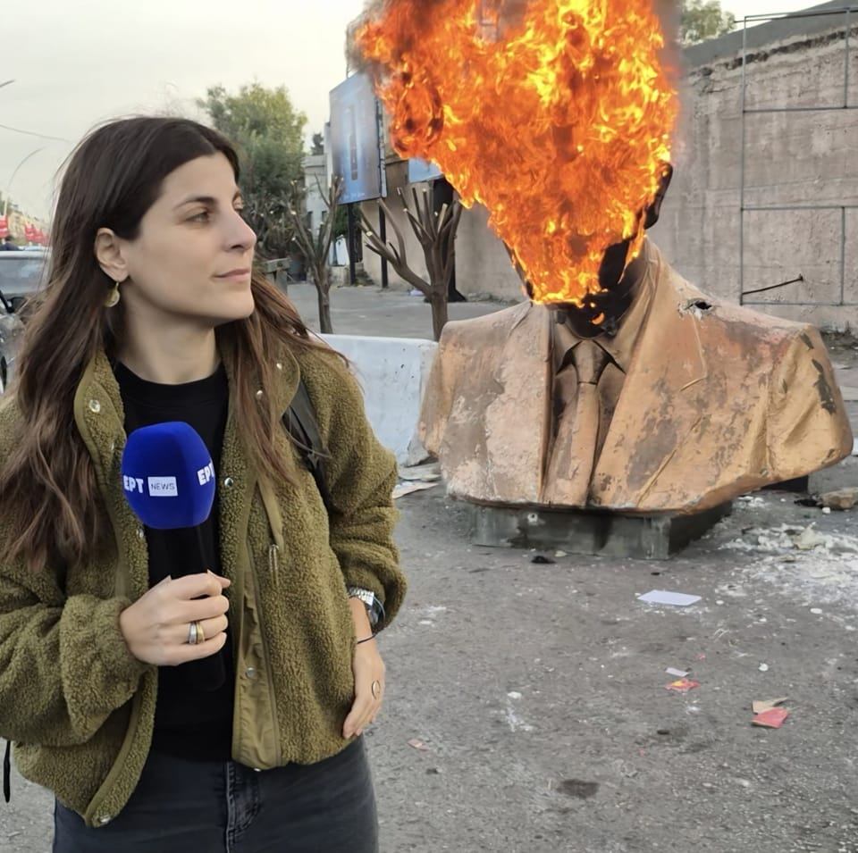 Elvira Krithari in Damascus, holding the ERT microphone in front of a burning bust statue.